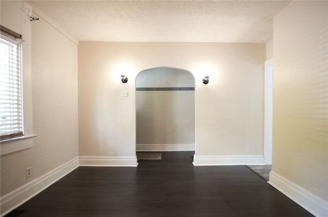 unfurnished room with dark wood-type flooring and a textured ceiling