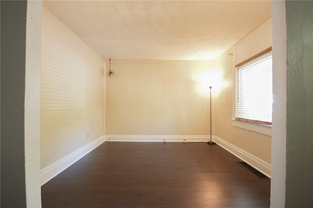 empty room featuring ornamental molding and dark wood-type flooring