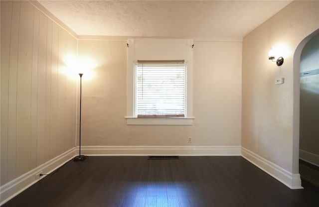 empty room featuring dark wood-type flooring and a textured ceiling