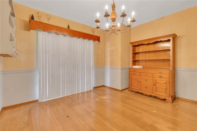 unfurnished dining area featuring light wood-type flooring and a notable chandelier