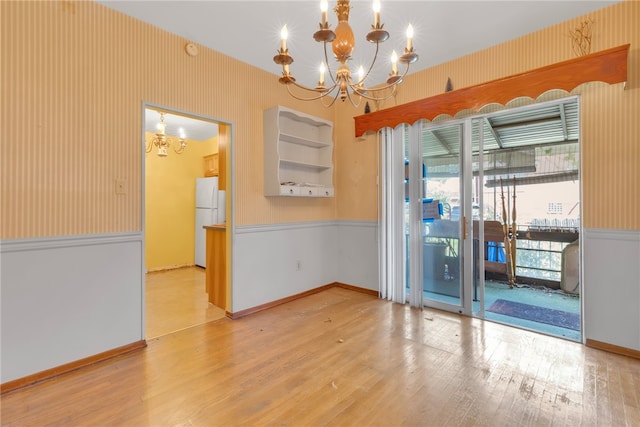 spare room featuring a chandelier and light hardwood / wood-style flooring