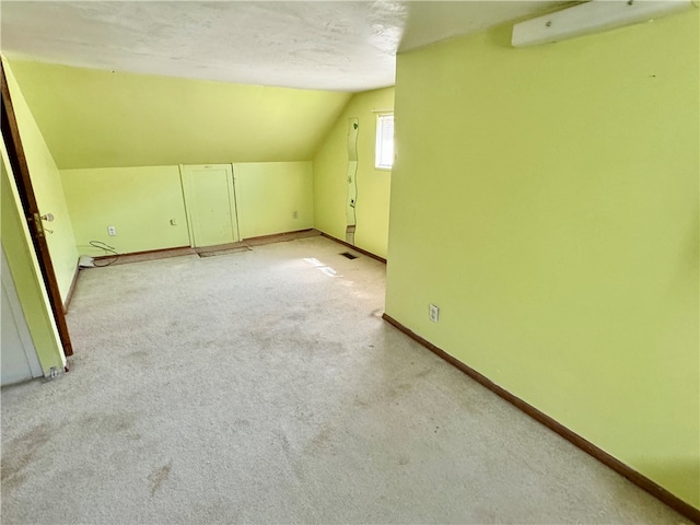 bonus room featuring light carpet, a textured ceiling, and lofted ceiling