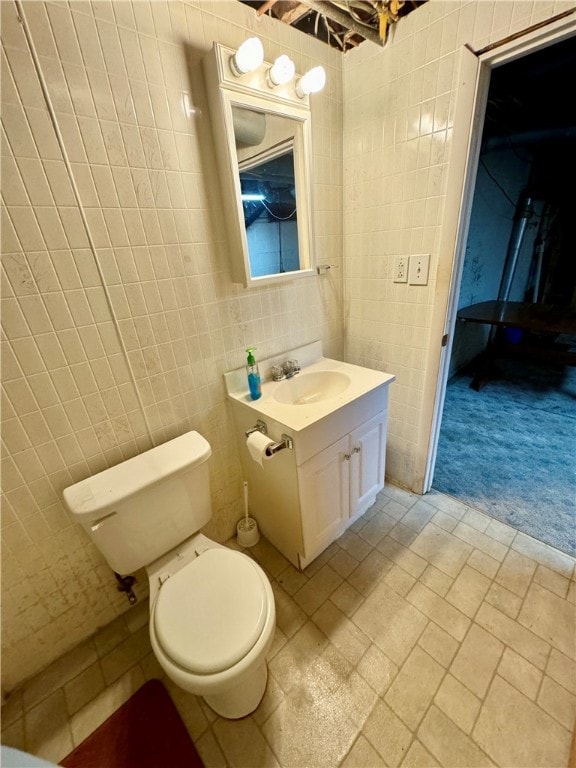 bathroom with toilet, vanity, and tile walls