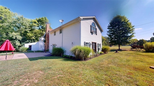 view of side of property featuring a lawn and a patio area