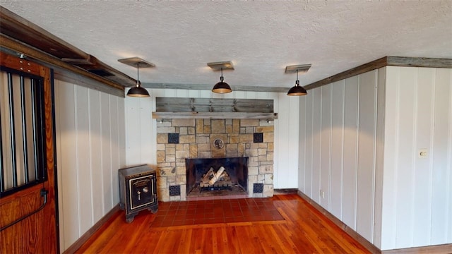 unfurnished living room featuring dark wood-type flooring, a fireplace, wooden walls, and a textured ceiling