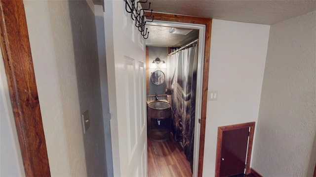 hallway with a textured ceiling and hardwood / wood-style flooring