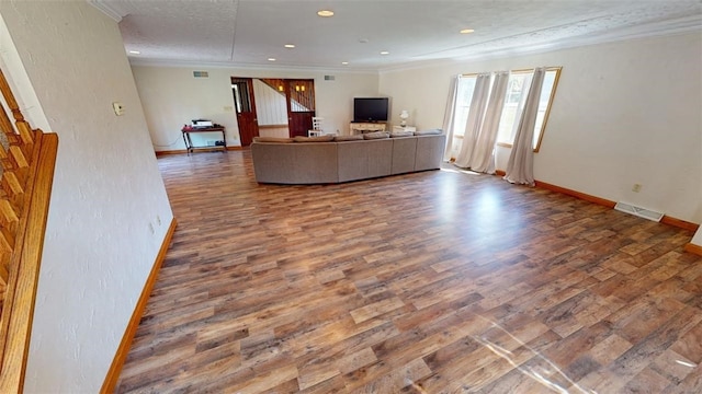 living room with a textured ceiling, crown molding, and wood-type flooring