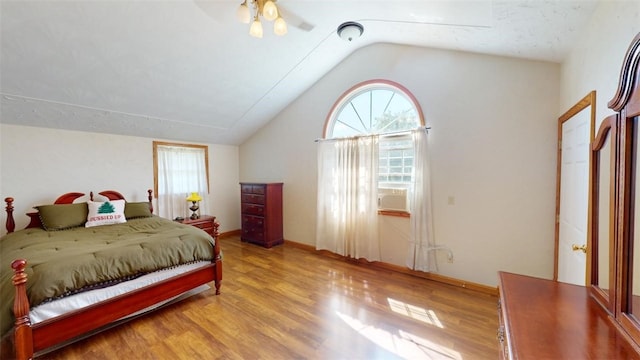 bedroom featuring light wood-type flooring, multiple windows, and vaulted ceiling