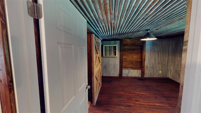 hallway featuring dark wood-type flooring and wood walls