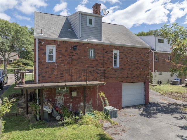 rear view of house with a garage and central AC unit