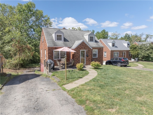 cape cod home featuring a front yard