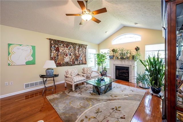 living room with lofted ceiling, wood-type flooring, a textured ceiling, and ceiling fan