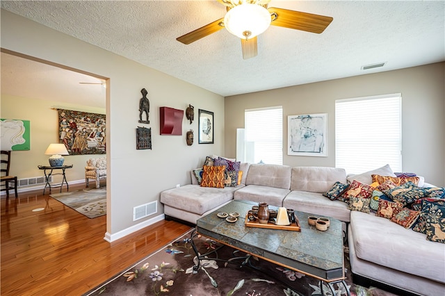 living room with ceiling fan, wood-type flooring, and a textured ceiling