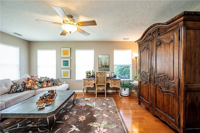 living room featuring plenty of natural light, a textured ceiling, light hardwood / wood-style flooring, and ceiling fan