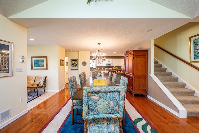 dining room featuring hardwood / wood-style floors, a notable chandelier, and a textured ceiling