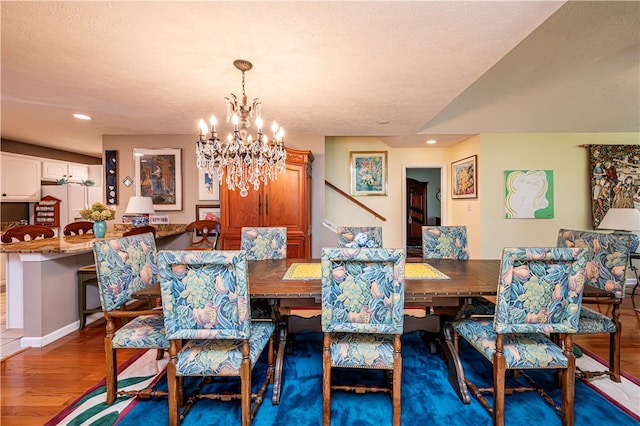 dining area with a textured ceiling, a chandelier, and hardwood / wood-style flooring