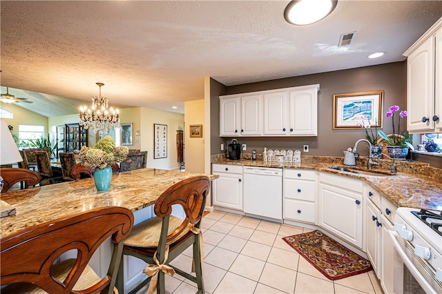 kitchen featuring pendant lighting, ceiling fan with notable chandelier, white appliances, sink, and light stone countertops