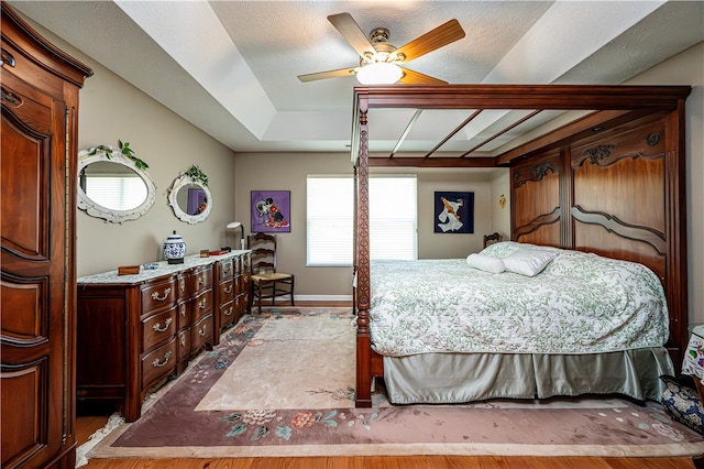 bedroom with a textured ceiling, wood-type flooring, and ceiling fan