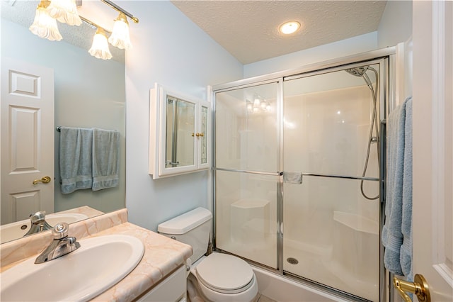 bathroom featuring vanity, toilet, a textured ceiling, and a shower with door