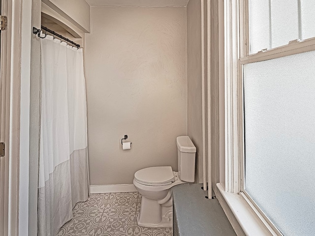 bathroom featuring toilet, a shower with curtain, and tile patterned floors