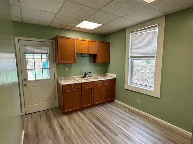 kitchen with a paneled ceiling, sink, and light hardwood / wood-style floors