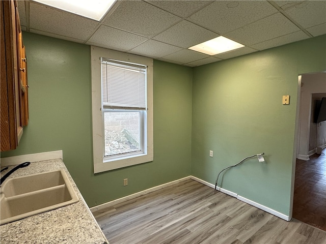 kitchen with light wood-type flooring, a paneled ceiling, and sink