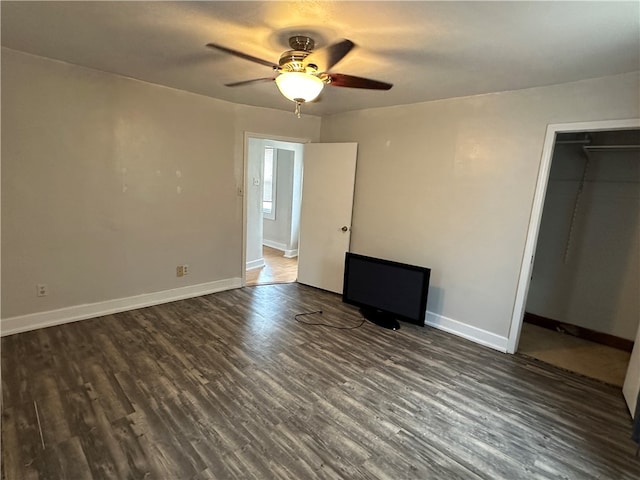 unfurnished bedroom with a closet, a spacious closet, ceiling fan, and dark hardwood / wood-style floors