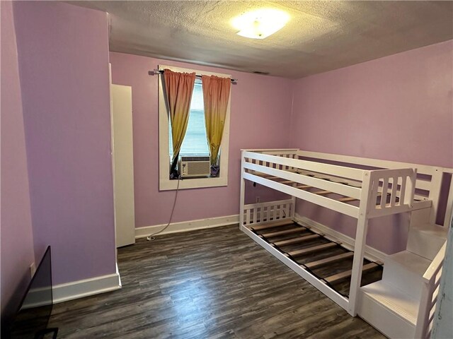 unfurnished bedroom with dark wood-type flooring, cooling unit, and a textured ceiling