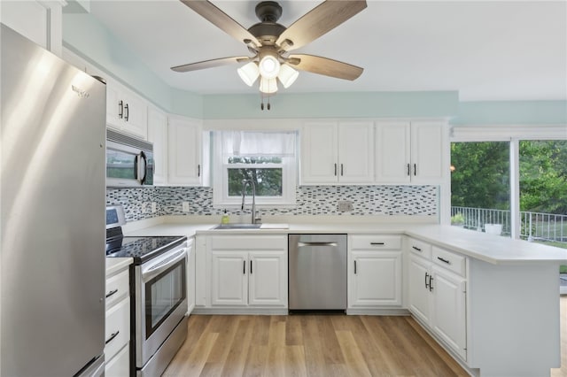 kitchen with light wood-type flooring, stainless steel appliances, sink, ceiling fan, and decorative backsplash