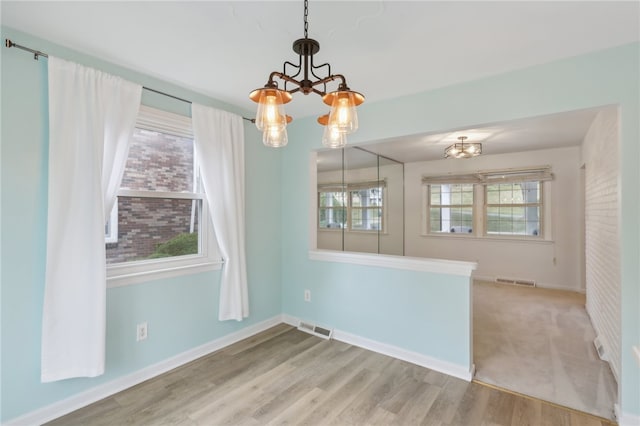 interior space with a healthy amount of sunlight, hardwood / wood-style floors, and a notable chandelier