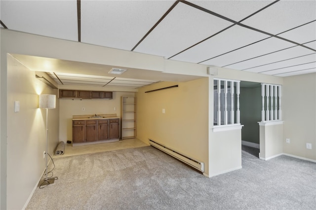 basement with light colored carpet, baseboard heating, and sink