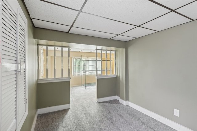 carpeted empty room featuring a paneled ceiling