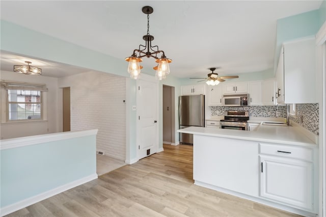 kitchen featuring ceiling fan with notable chandelier, appliances with stainless steel finishes, light hardwood / wood-style flooring, and decorative light fixtures