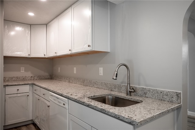 kitchen with white cabinets, light stone counters, sink, and white dishwasher