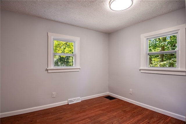 unfurnished room with wood-type flooring and a textured ceiling