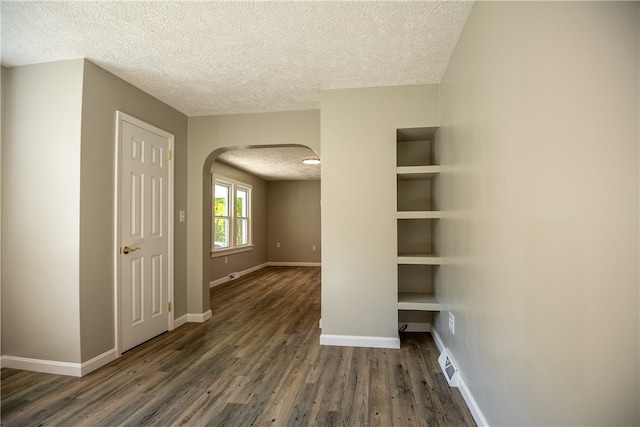 spare room featuring a textured ceiling, dark hardwood / wood-style flooring, and built in shelves