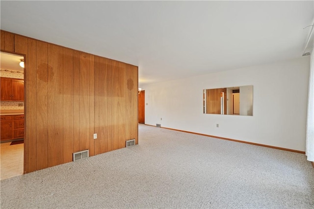 carpeted spare room featuring wooden walls