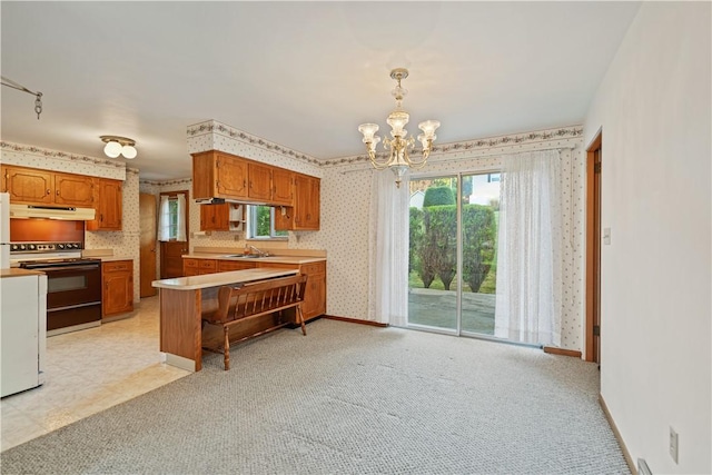 kitchen featuring range with electric cooktop, sink, a chandelier, pendant lighting, and light carpet