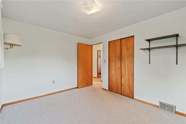 unfurnished bedroom with light colored carpet and a closet