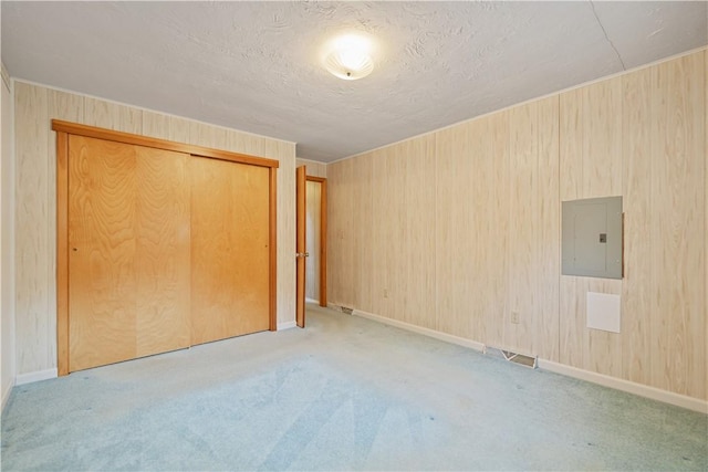 unfurnished bedroom featuring electric panel, a closet, and light colored carpet