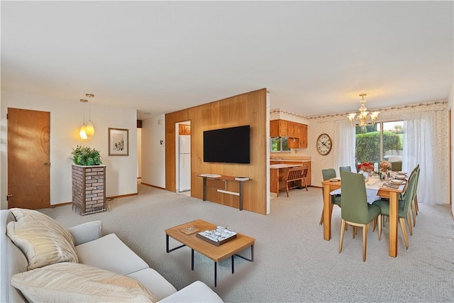 living room featuring light carpet, an inviting chandelier, and wood walls