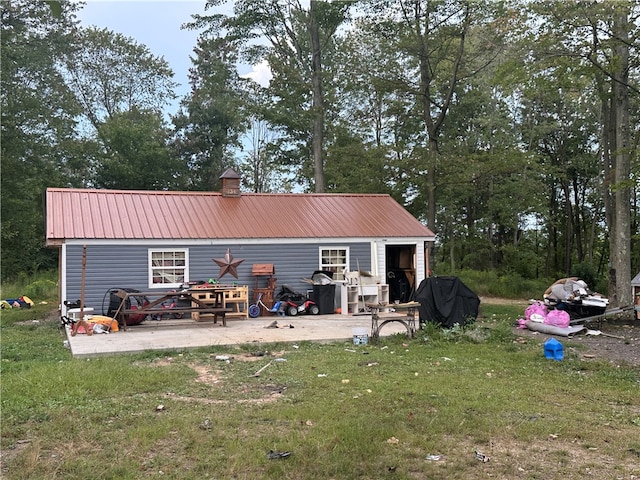 back of property featuring an outbuilding, a lawn, and a patio area