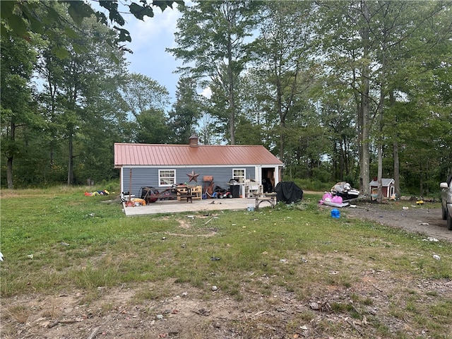 rear view of house featuring a yard, a shed, and a patio