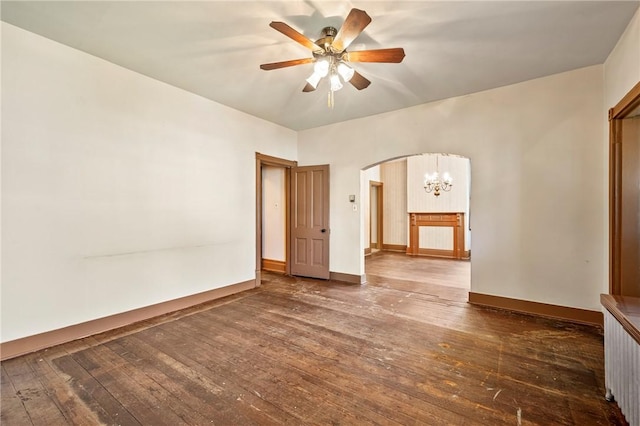 spare room with ceiling fan with notable chandelier and dark hardwood / wood-style flooring