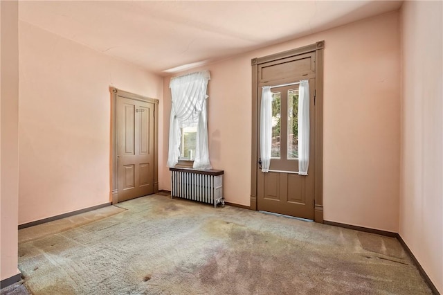 empty room with light colored carpet and radiator heating unit