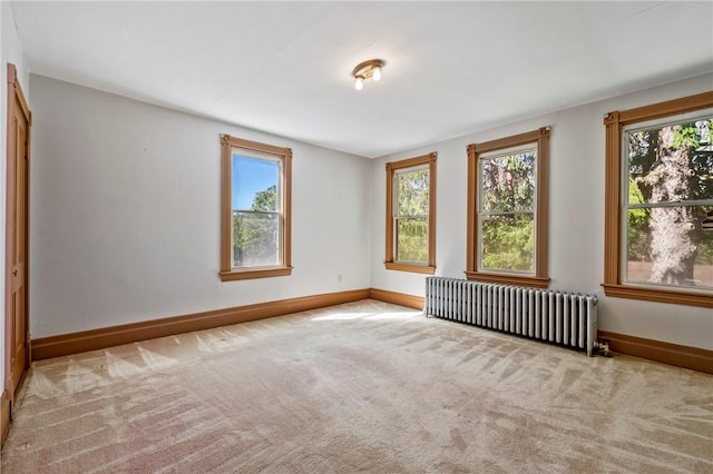 unfurnished room featuring light colored carpet and radiator heating unit