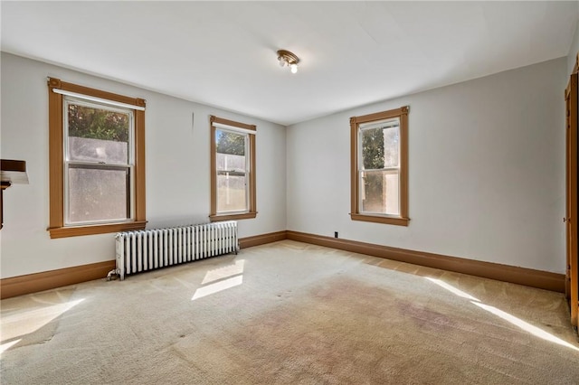 spare room with light carpet and radiator