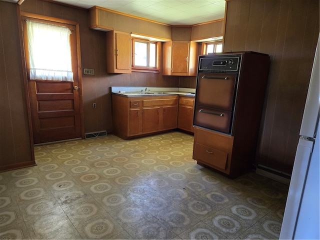 kitchen featuring wood walls, sink, and white refrigerator