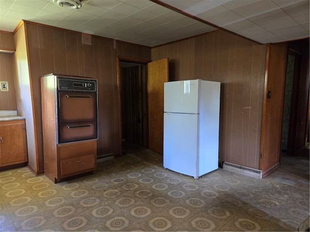 kitchen with oven, wooden walls, and white fridge