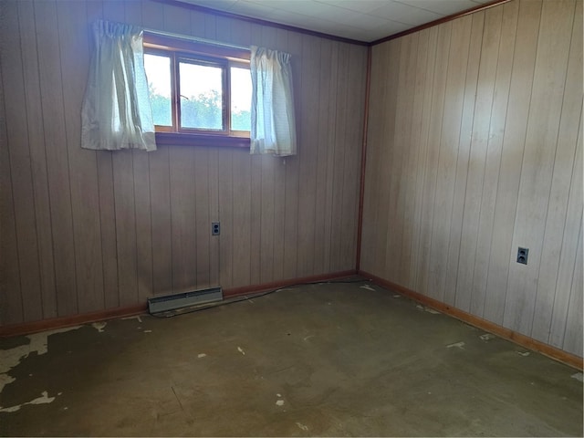 spare room featuring a baseboard radiator, wooden walls, and concrete flooring